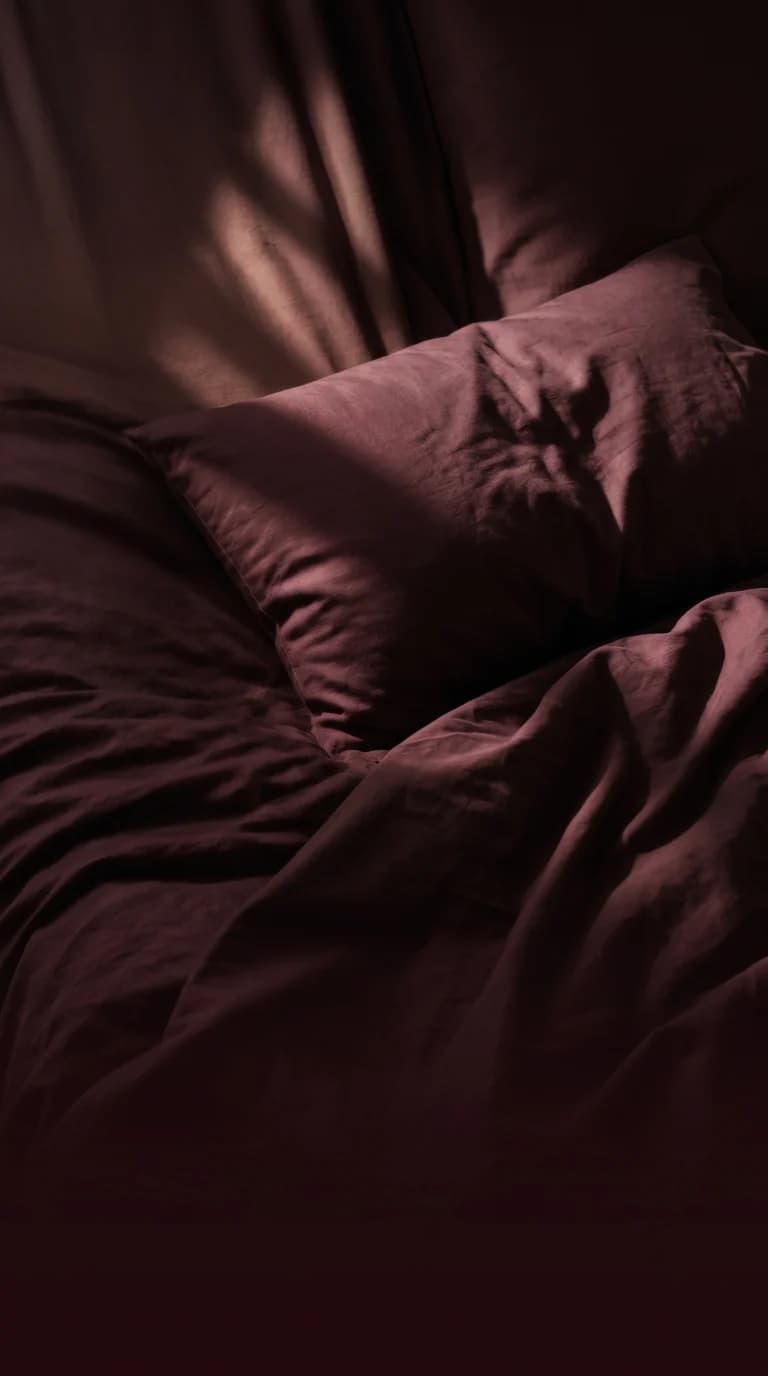 Burgundy bed linens in low evening light